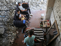 A barber is cutting the hair of a man in the ruins of his destroyed salon, which was destroyed by Israeli strikes, in al-Bureij refugee camp...