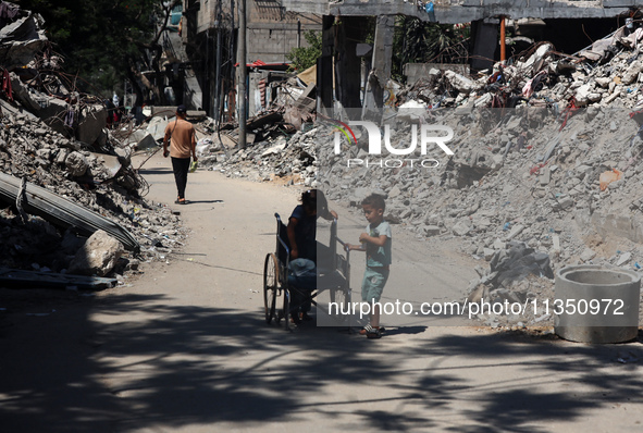 Palestinians are making their way past destroyed buildings in al-Bureij refugee camp in the central Gaza Strip, on June 22, 2024, amid the o...