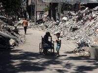 Palestinians are making their way past destroyed buildings in al-Bureij refugee camp in the central Gaza Strip, on June 22, 2024, amid the o...