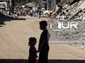 Palestinians are making their way past destroyed buildings in al-Bureij refugee camp in the central Gaza Strip, on June 22, 2024, amid the o...