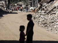 Palestinians are making their way past destroyed buildings in al-Bureij refugee camp in the central Gaza Strip, on June 22, 2024, amid the o...