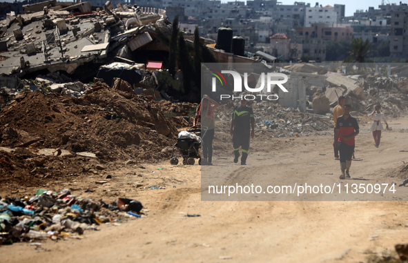 Palestinians are making their way past destroyed buildings in al-Bureij refugee camp in the central Gaza Strip, on June 22, 2024, amid the o...