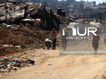 Palestinians are making their way past destroyed buildings in al-Bureij refugee camp in the central Gaza Strip, on June 22, 2024, amid the o...