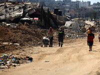 Palestinians are making their way past destroyed buildings in al-Bureij refugee camp in the central Gaza Strip, on June 22, 2024, amid the o...