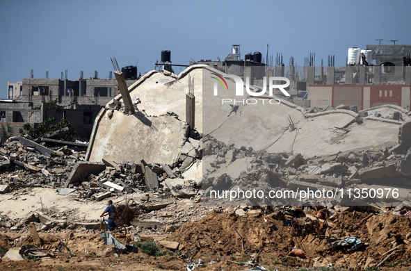 Palestinians are making their way past destroyed buildings in al-Bureij refugee camp in the central Gaza Strip, on June 22, 2024, amid the o...