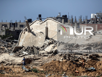 Palestinians are making their way past destroyed buildings in al-Bureij refugee camp in the central Gaza Strip, on June 22, 2024, amid the o...