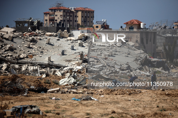 Palestinians are making their way past destroyed buildings in al-Bureij refugee camp in the central Gaza Strip, on June 22, 2024, amid the o...