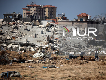 Palestinians are making their way past destroyed buildings in al-Bureij refugee camp in the central Gaza Strip, on June 22, 2024, amid the o...