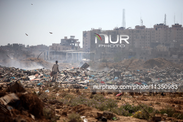 Palestinian men are searching for recyclables at a garbage dump in al-Bureij refugee camp in the central Gaza Strip, on June 22, 2024, amid...