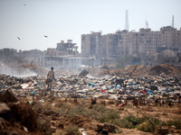 Palestinian men are searching for recyclables at a garbage dump in al-Bureij refugee camp in the central Gaza Strip, on June 22, 2024, amid...