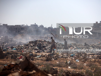 Palestinian men are searching for recyclables at a garbage dump in al-Bureij refugee camp in the central Gaza Strip, on June 22, 2024, amid...