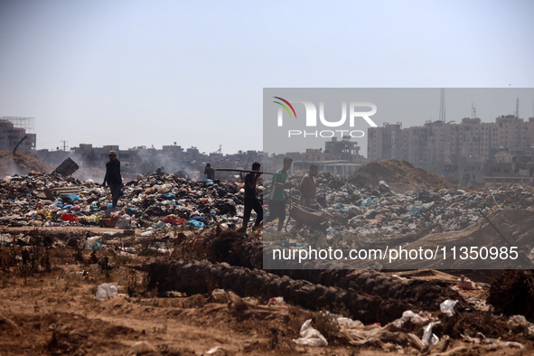 Palestinian men are searching for recyclables at a garbage dump in al-Bureij refugee camp in the central Gaza Strip, on June 22, 2024, amid...