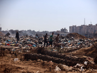 Palestinian men are searching for recyclables at a garbage dump in al-Bureij refugee camp in the central Gaza Strip, on June 22, 2024, amid...