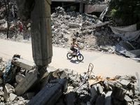 A Palestinian boy is riding his bicycle past destroyed buildings in al-Bureij refugee camp in the central Gaza Strip, on June 22, 2024, amid...