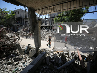 Palestinians are making their way past destroyed buildings in al-Bureij refugee camp in the central Gaza Strip, on June 22, 2024, amid the o...