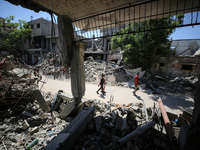 Palestinians are making their way past destroyed buildings in al-Bureij refugee camp in the central Gaza Strip, on June 22, 2024, amid the o...