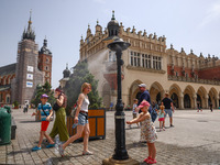 People walk by a water mist sprinkler at the Main Square in Krakow, Poland on June 21, 2024. (