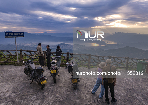 Tourists are watching the sunrise from a viewing platform on the Three Gorges Dam in Yichang, China, on June 23, 2024. 