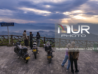 Tourists are watching the sunrise from a viewing platform on the Three Gorges Dam in Yichang, China, on June 23, 2024. (