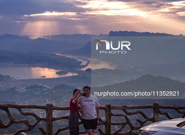 Tourists are watching the sunrise from a viewing platform on the Three Gorges Dam in Yichang, China, on June 23, 2024. 