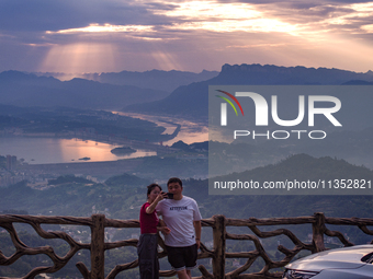 Tourists are watching the sunrise from a viewing platform on the Three Gorges Dam in Yichang, China, on June 23, 2024. (