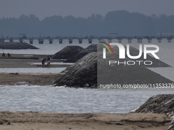 Workers are scooping up oil-stained sand at East Coast Park beach in Singapore, on June 23, 2024. Singapore authorities are continuing clean...