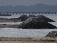 Workers are scooping up oil-stained sand at East Coast Park beach in Singapore, on June 23, 2024. Singapore authorities are continuing clean...