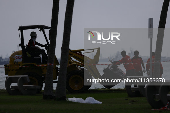 Workers are loading bags of oil-stained sand onto a wheel loader at East Coast Park beach in Singapore, on June 23, 2024. Singapore authorit...