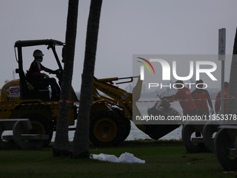 Workers are loading bags of oil-stained sand onto a wheel loader at East Coast Park beach in Singapore, on June 23, 2024. Singapore authorit...