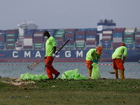 Workers are scooping up oil-stained sand at East Coast Park beach in Singapore, on June 23, 2024. Singapore authorities are continuing clean...