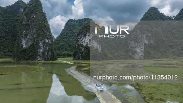 Vehicles are driving on a ''water highway'' formed by floods along a rural road in Chongzuo, China, on June 23, 2024. 