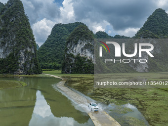 Vehicles are driving on a ''water highway'' formed by floods along a rural road in Chongzuo, China, on June 23, 2024. (