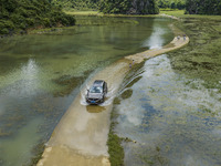 Vehicles are driving on a ''water highway'' formed by floods along a rural road in Chongzuo, China, on June 23, 2024. (