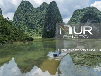 Vehicles are driving on a ''water highway'' formed by floods along a rural road in Chongzuo, China, on June 23, 2024. (