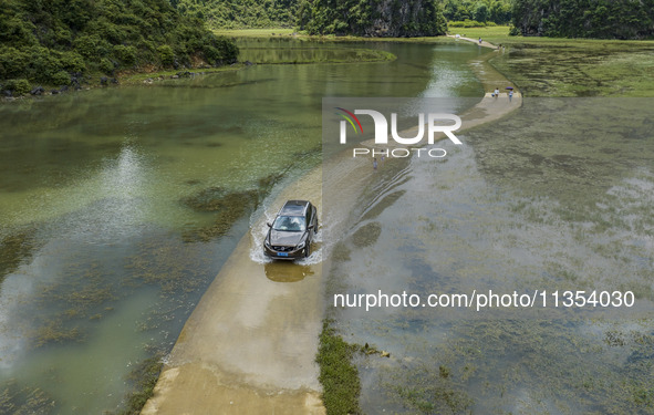 Vehicles are driving on a ''water highway'' formed by floods along a rural road in Chongzuo, China, on June 23, 2024. 