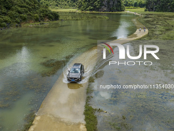 Vehicles are driving on a ''water highway'' formed by floods along a rural road in Chongzuo, China, on June 23, 2024. (