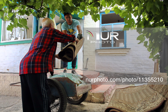 Two men are throwing away damaged belongings outside a house after a Russian missile attack in Vasylkiv, Ukraine, on June 23, 2024. On Sunda...