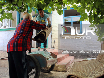 Two men are throwing away damaged belongings outside a house after a Russian missile attack in Vasylkiv, Ukraine, on June 23, 2024. On Sunda...