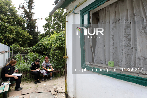 Police officers are helping a woman outside a damaged house after a Russian missile attack in Vasylkiv, Ukraine, on June 23, 2024. On Sunday...