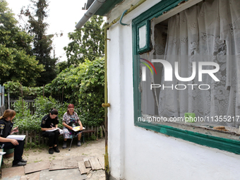 Police officers are helping a woman outside a damaged house after a Russian missile attack in Vasylkiv, Ukraine, on June 23, 2024. On Sunday...