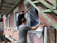 Men are sealing a knocked-out window with a film after a Russian missile attack in Vasylkiv, Ukraine, on June 23, 2024. On Sunday morning, J...