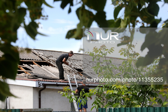 Two men are repairing the roof of a house damaged by a Russian missile attack in Vasylkiv, Ukraine, on June 23, 2024. On Sunday morning, Jun...