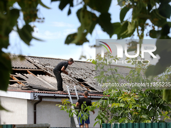 Two men are repairing the roof of a house damaged by a Russian missile attack in Vasylkiv, Ukraine, on June 23, 2024. On Sunday morning, Jun...