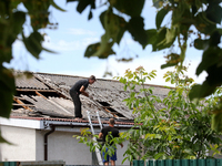 Two men are repairing the roof of a house damaged by a Russian missile attack in Vasylkiv, Ukraine, on June 23, 2024. On Sunday morning, Jun...