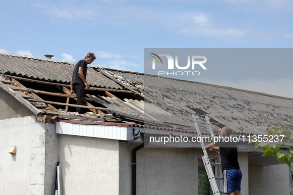 Two men are repairing the roof of a house damaged by a Russian missile attack in Vasylkiv, Ukraine, on June 23, 2024. On Sunday morning, Jun...