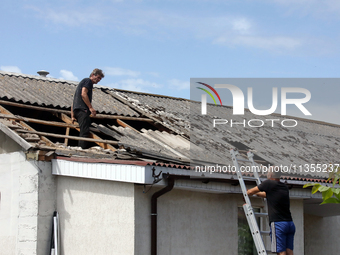 Two men are repairing the roof of a house damaged by a Russian missile attack in Vasylkiv, Ukraine, on June 23, 2024. On Sunday morning, Jun...