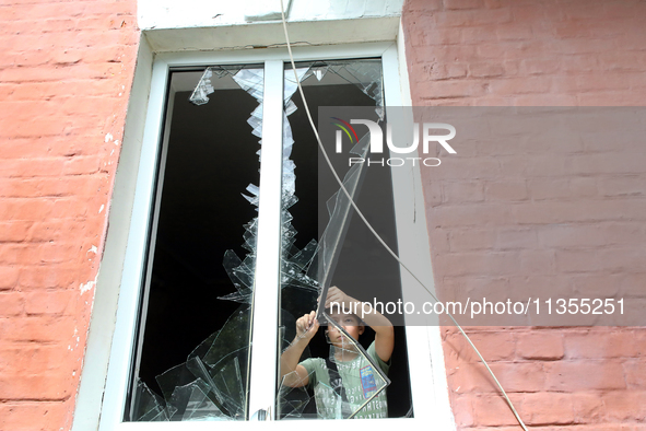 A boy is removing broken glass at a house after a Russian missile attack in Vasylkiv, Kyiv region, northern Ukraine, on June 23, 2024. On Su...