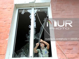 A boy is removing broken glass at a house after a Russian missile attack in Vasylkiv, Kyiv region, northern Ukraine, on June 23, 2024. On Su...