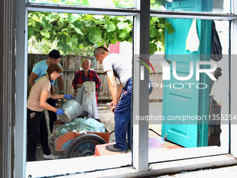 People are removing the debris as seen through a window of a house after a Russian missile attack in Vasylkiv, Ukraine, on June 23, 2024. On...