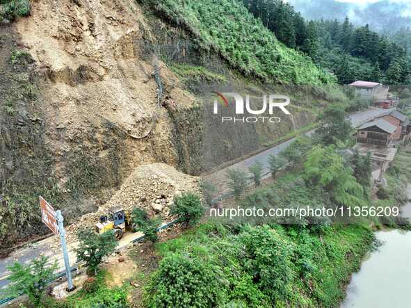 Workers are driving machinery and equipment to clear landslide soil at the site of a landslide in Datong Township on G242 National Highway i...